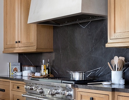 Chef's kitchen with custom cabinetry, marble top island with Wolf stove and large vent hood in Houston, TX.