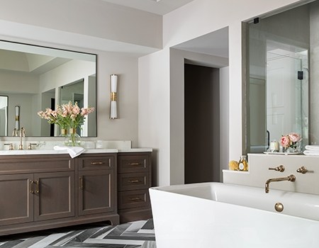 Large high-end master bathroom with marble in herringbone flooring, massive soaking tub, separate shower and dual vanities with brass fixtures in Houston, TX