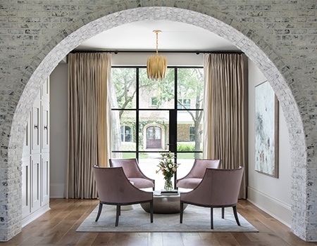 Sitting parlor with arched exposed white washed brick black steel windows with beautiful wood floors and custom floor to ceiling cabinets in Houston, TX