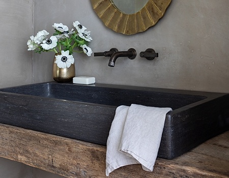 Custom powder bathroom with wooden counter top and antique black sink and black hardware and a gold framed mirror in Houston, TX