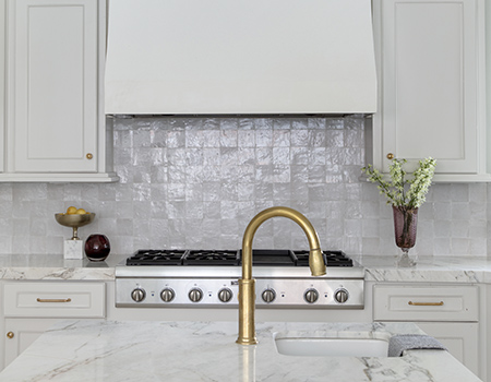 Custom checf kitchen with brass fixture sink and chef stove with large vent hood. Custom tile backsplash detail in Houston, TX