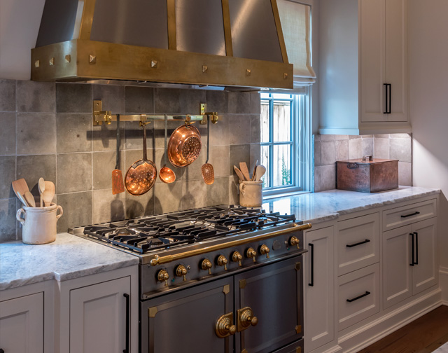 Carrara marble kitchen with luxury range and custom pot holder detail in Houston, TX